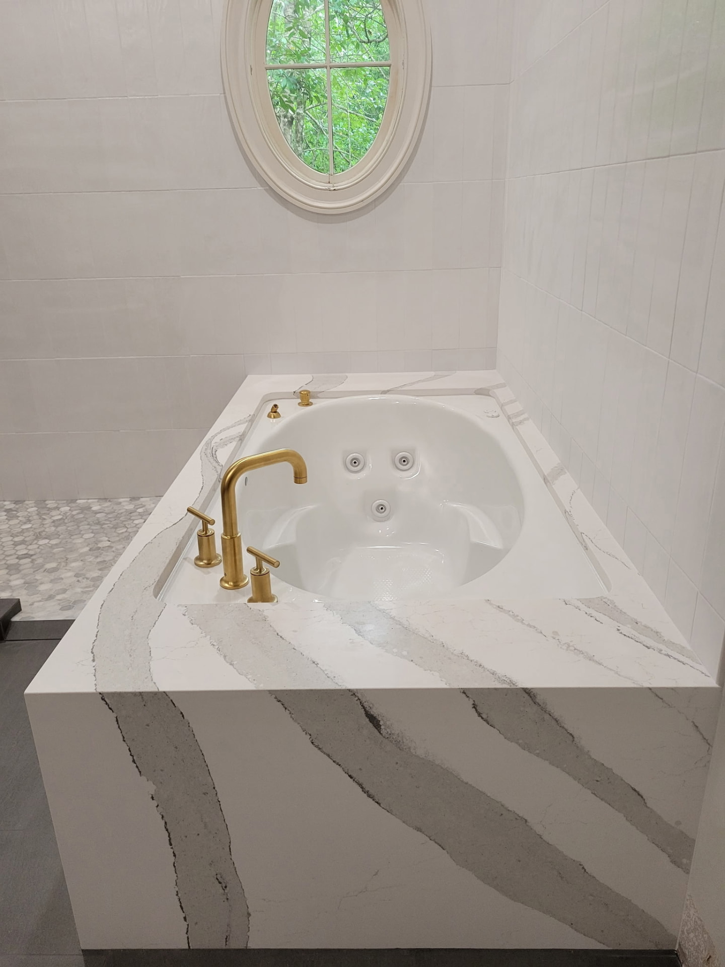 Quartz-surround jacuzzi tub deck with brushed gold tub filler installed by Big Branch Plumbing in Mandeville, LA