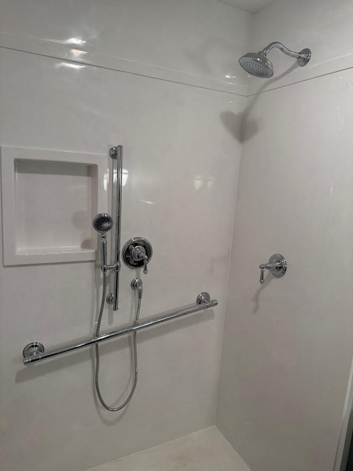 Accessible shower with chrome ADA grab bars, slide bar hand shower and shower head installed by Big Branch Plumbing