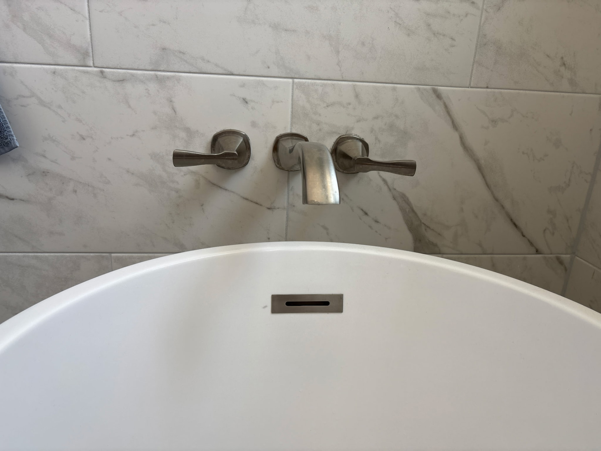 Wall-mounted brushed nickel tub filler set over a freestanding tub installed by Big Branch Plumbing